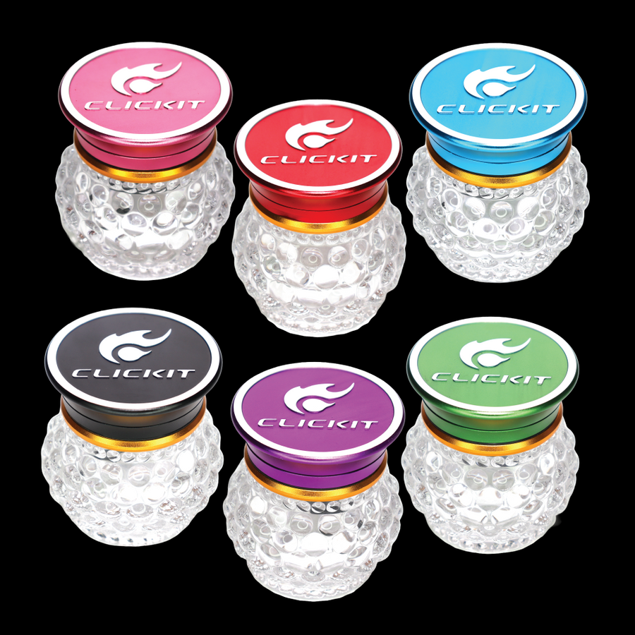 Six CLICKIT MG-107 63 mm Diamond Ball grinders with textured clear glass bodies, gold-tone rings, and assorted metallic pink, red, blue, black, purple, and green tops.